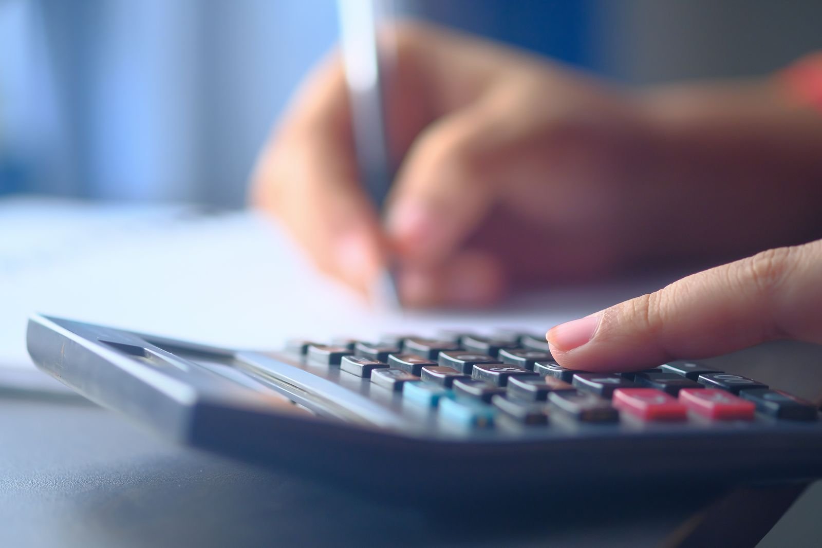 e.Sentral Maintenance Fee & the Real Cost of Ownership (2026) 1 Hands using a calculator and pen over paperwork at a desk, working out monthly property costs