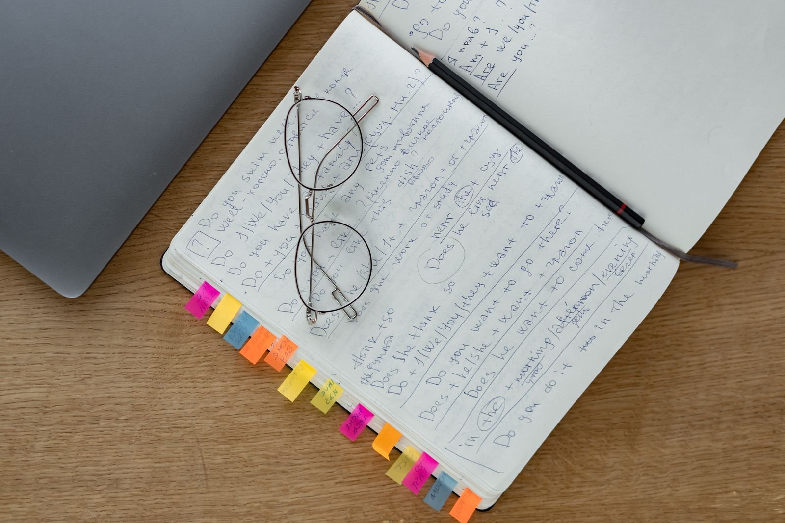 Affordable Condos Under RM500k near Sungai Buloh & Subang Bestari (2026) 2 Overhead view of an open notebook with handwritten notes, coloured tabs, a pencil and reading glasses on a desk