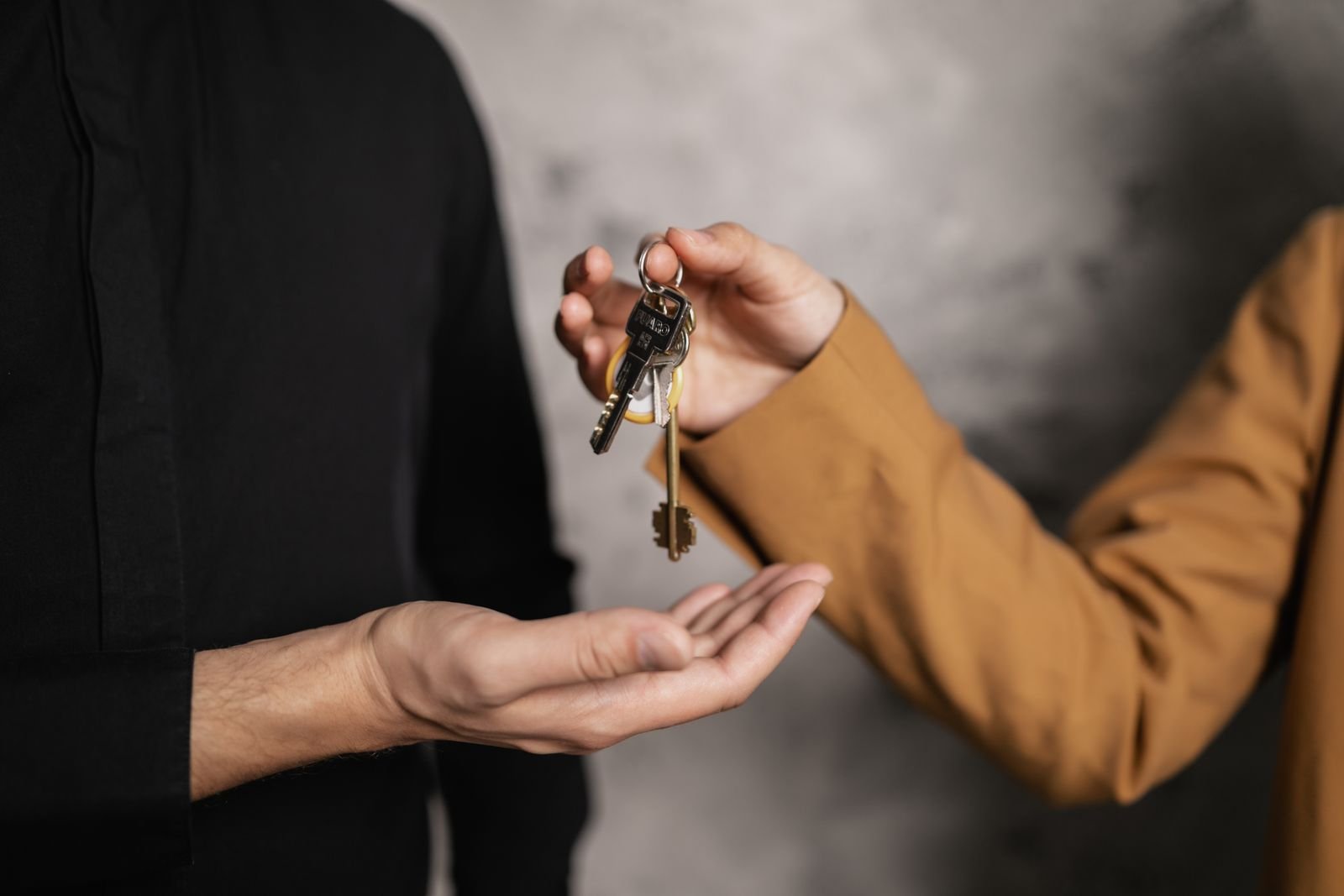 Close-up of one person passing a bunch of house keys into another person's open hand