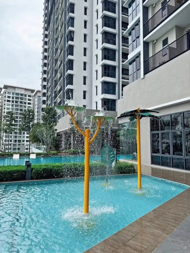 Kuchai Uptown swimming pool with water-play features at the podium facilities deck, residential tower behind